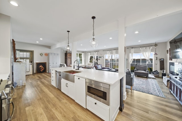 kitchen with open floor plan, light wood finished floors, a sink, and stainless steel appliances