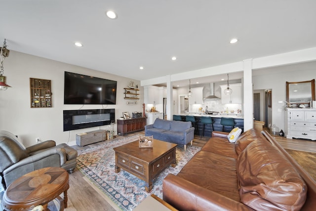 living room featuring a glass covered fireplace, recessed lighting, and light wood finished floors