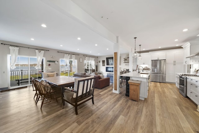 kitchen with light wood-type flooring, recessed lighting, open floor plan, light countertops, and appliances with stainless steel finishes