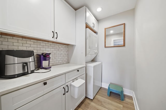 clothes washing area with recessed lighting, stacked washing maching and dryer, light wood-style flooring, and baseboards
