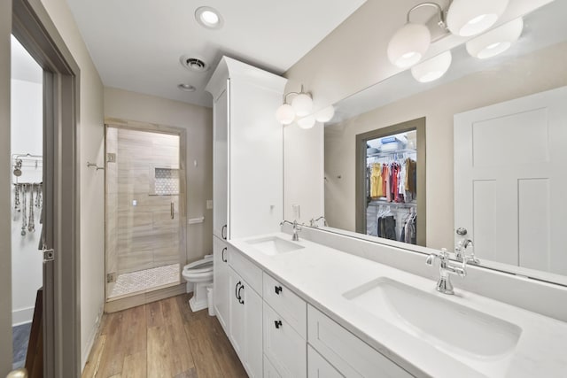full bathroom with a shower stall, double vanity, a sink, and toilet