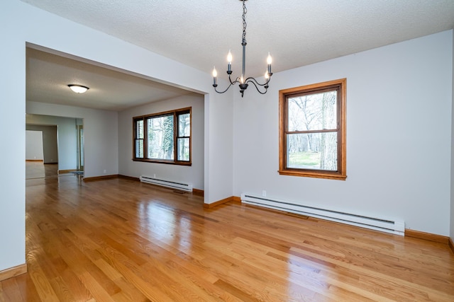 2532 Ridgewood Trl, Berrien Springs, MI 49103 - unfurnished room with baseboards, baseboard heating, light wood-type flooring, and an inviting chandelier