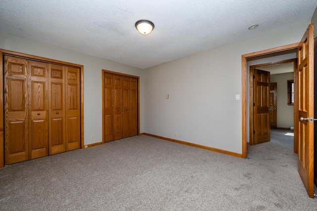 2532 Ridgewood Trl, Berrien Springs, MI 49103 - unfurnished bedroom with multiple closets, light colored carpet, baseboards, and a textured ceiling
