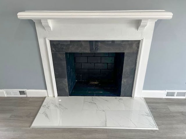 4651 Berkshire St, Detroit, MI 48224 - details with a tiled fireplace, visible vents, baseboards, and wood finished floors