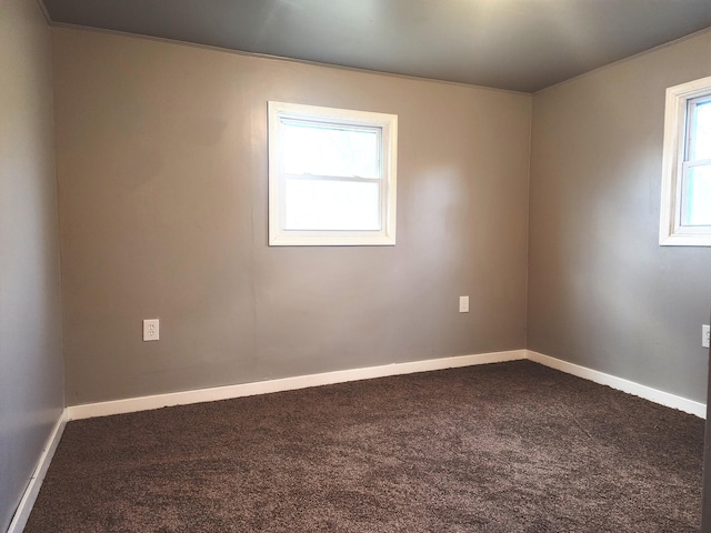 empty room featuring dark carpet and baseboards