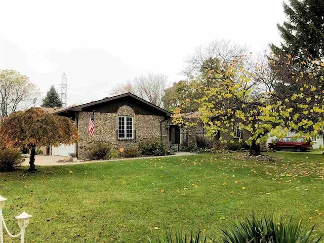 view of front of home with a front yard, an attached garage, and brick siding