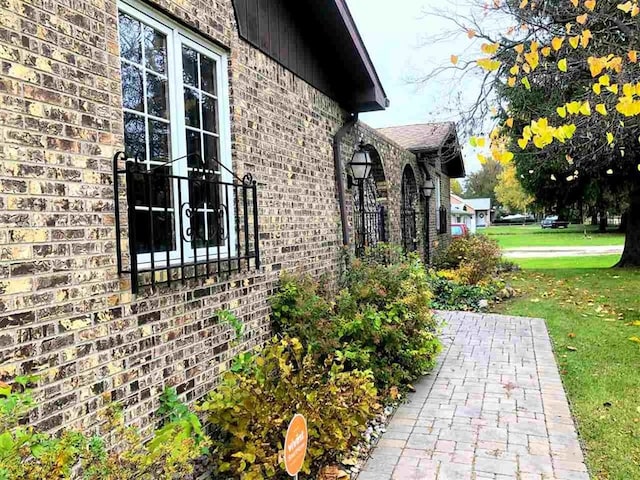 view of side of home with brick siding and a yard