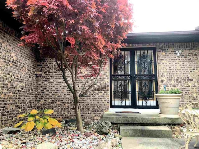 entrance to property featuring french doors and brick siding