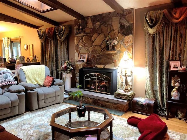 living area featuring beam ceiling, wood finished floors, and a lit fireplace