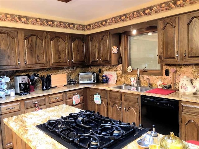 kitchen featuring dishwasher, a sink, stovetop, and tasteful backsplash