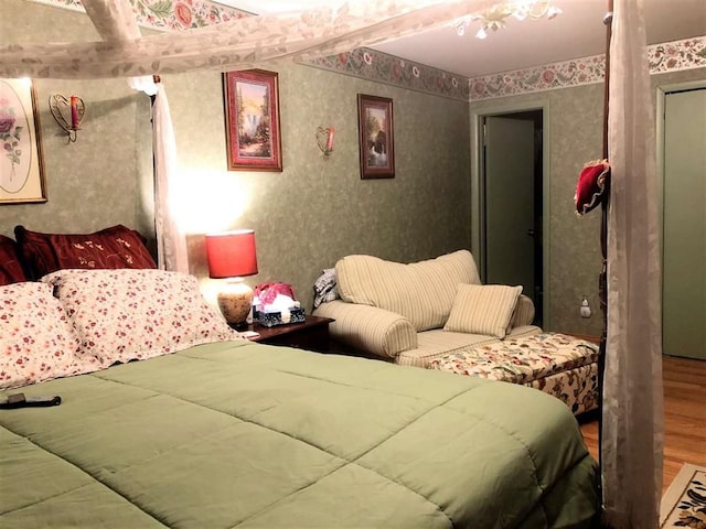 bedroom with wood finished floors and wallpapered walls