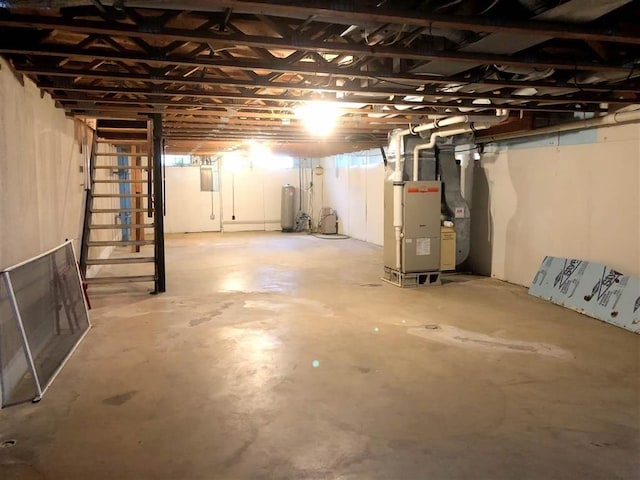 unfinished basement featuring heating unit and a water pressure tank