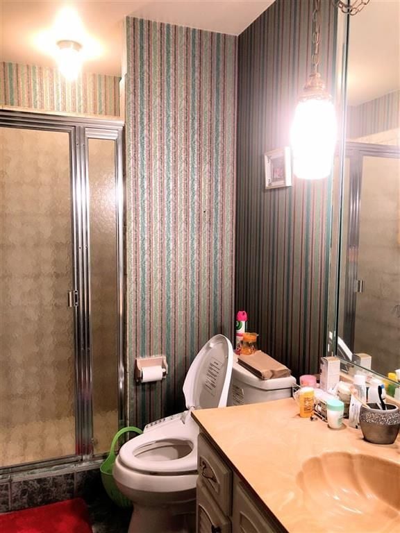 full bathroom featuring toilet, a stall shower, vanity, and wallpapered walls
