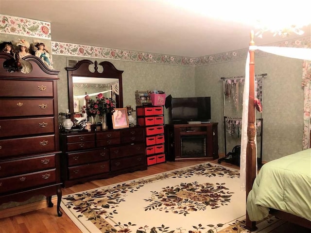 bedroom with wood finished floors and wallpapered walls