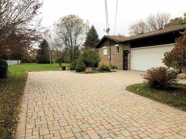 view of side of property with decorative driveway, a garage, and brick siding