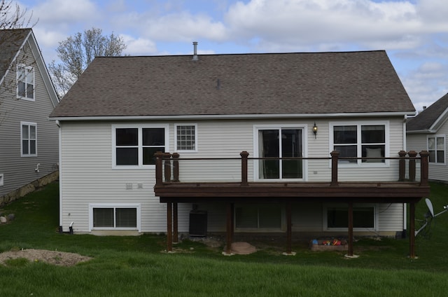 rear view of house featuring a yard, a deck, and roof with shingles