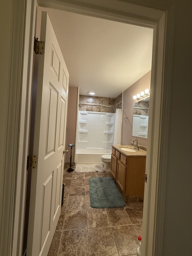 bathroom featuring shower / bath combo with shower curtain, stone finish floor, toilet, and vanity