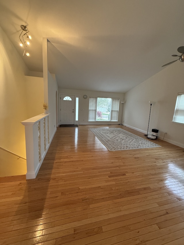 foyer featuring baseboards, a ceiling fan, vaulted ceiling, and light wood-style flooring