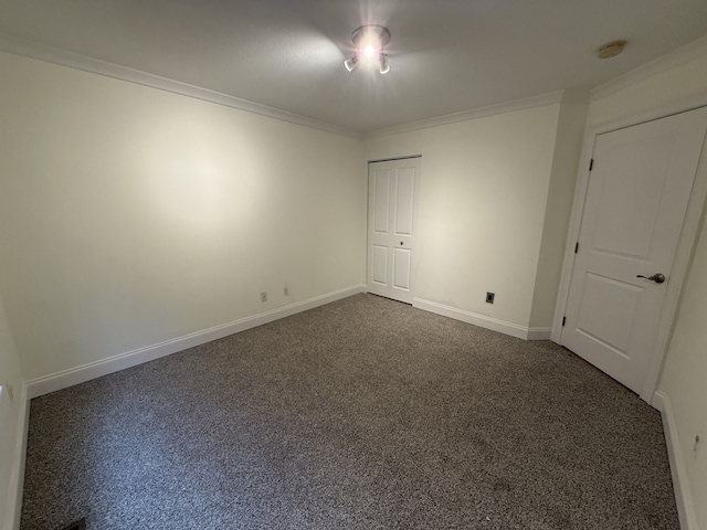 empty room featuring crown molding, baseboards, and dark carpet
