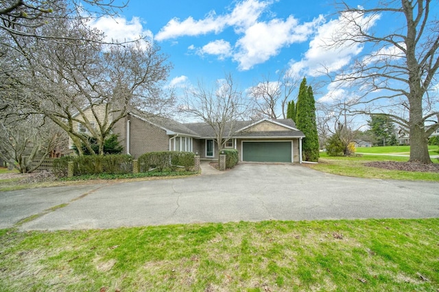 single story home with aphalt driveway, an attached garage, and a front yard