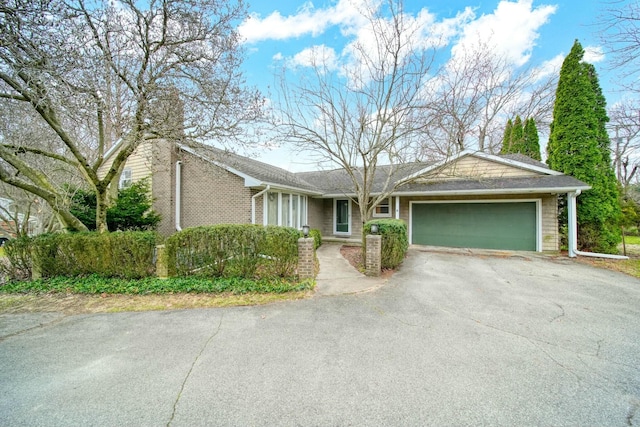 single story home featuring a garage, aphalt driveway, and brick siding