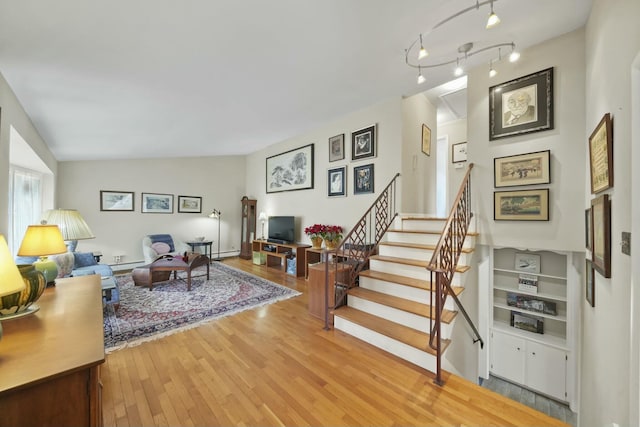 living room featuring light wood finished floors, stairway, and lofted ceiling