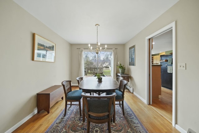 dining area featuring baseboard heating, light wood-style floors, an inviting chandelier, and baseboards