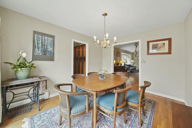 dining space with light wood finished floors, a baseboard radiator, an inviting chandelier, and baseboards
