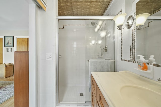 bathroom featuring a shower stall, vanity, and tile walls