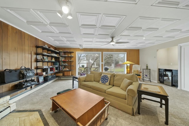 living room featuring wood walls, a baseboard radiator, a ceiling fan, and carpet floors