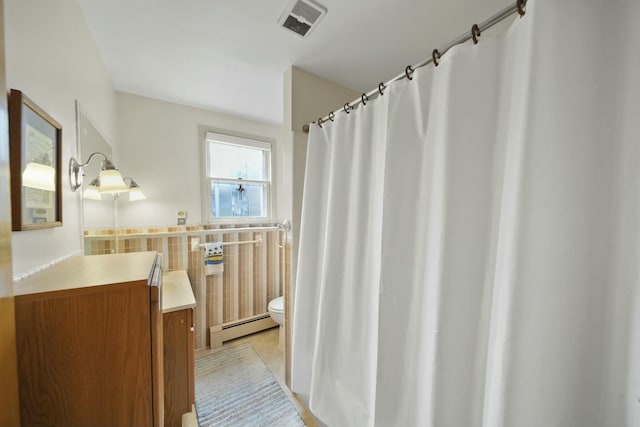 bathroom with visible vents, tile walls, toilet, baseboard heating, and vanity