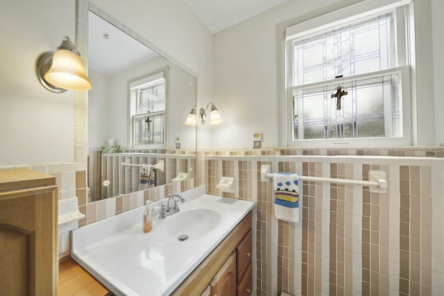 bathroom with tile walls, plenty of natural light, wainscoting, and vanity