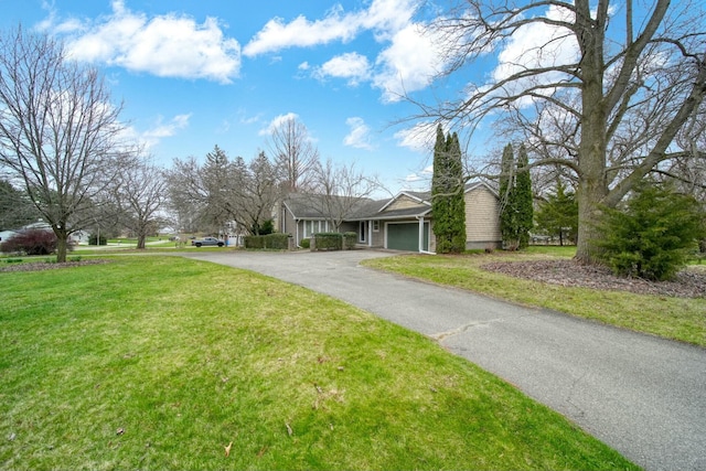 view of front of home featuring aphalt driveway, a front yard, a chimney, and an attached garage