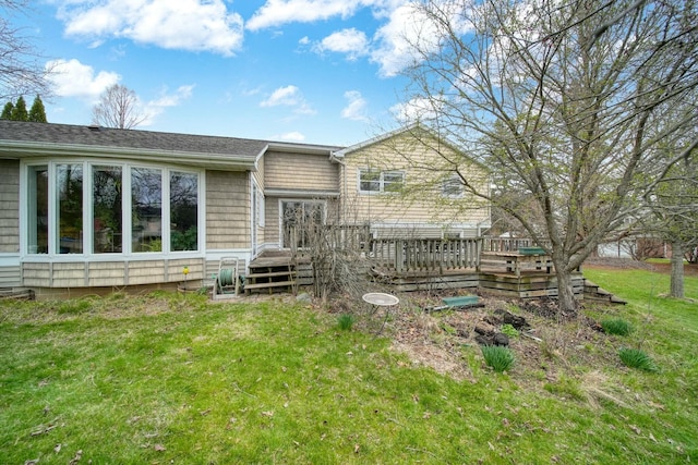 rear view of property featuring a wooden deck and a lawn