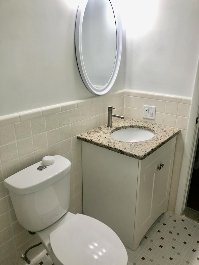 bathroom with vanity, toilet, wainscoting, tile walls, and tile patterned floors