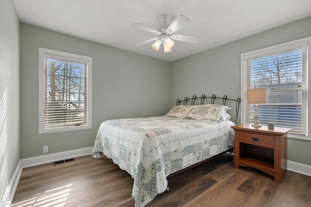 bedroom with a textured ceiling, wood finished floors, baseboards, and visible vents