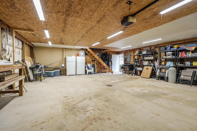 garage with a garage door opener, a workshop area, and freestanding refrigerator