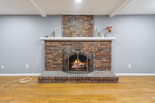 interior details with baseboards, wood finished floors, a fireplace, and beam ceiling