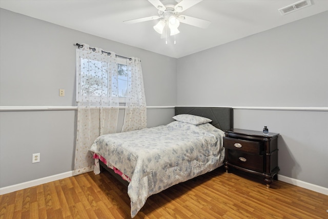 bedroom with visible vents, baseboards, and wood finished floors