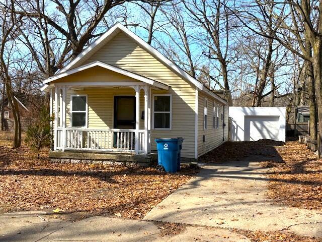 view of front of home with concrete driveway, a porch, and an outdoor structure