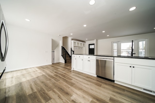 6522 Ellinwood Dr, White Lake, MI 48383 - kitchen featuring dark countertops, white cabinetry, recessed lighting, stainless steel appliances, and light wood-style flooring