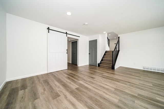 6522 Ellinwood Dr, White Lake, MI 48383 - unfurnished living room featuring recessed lighting, stairway, a barn door, visible vents, and wood finished floors