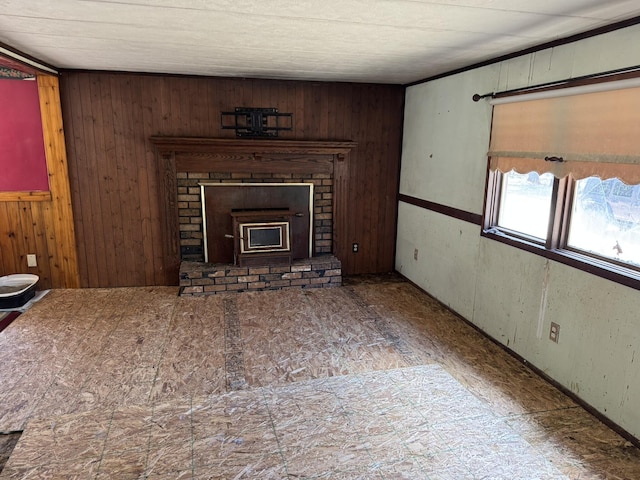 unfurnished living room with wood walls and a brick fireplace