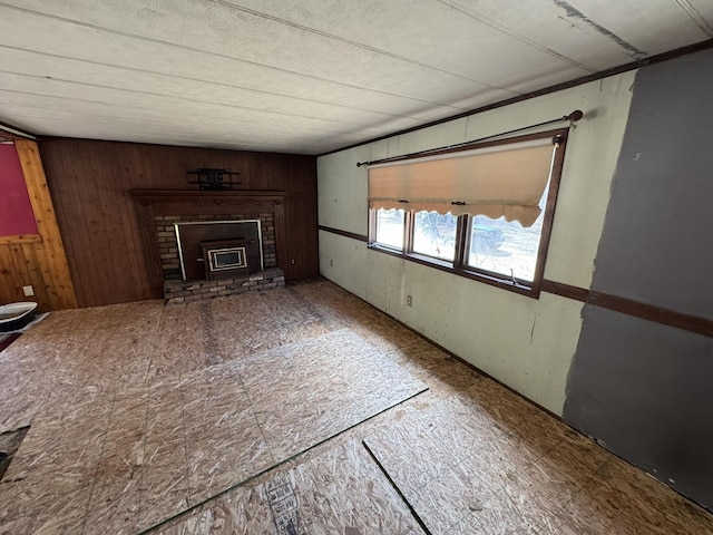 unfurnished living room with wood walls and a fireplace