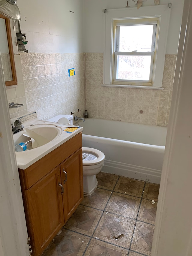 full bathroom featuring toilet, tile walls, a bathtub, wainscoting, and vanity