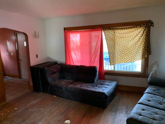 living room featuring arched walkways, hardwood / wood-style floors, and a textured ceiling