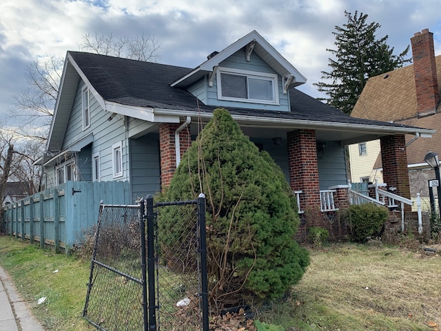 bungalow-style house featuring a shingled roof, brick siding, fence, and a gate