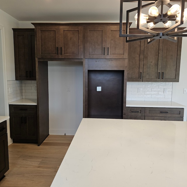 18468 Stallmann Dr, Macomb, MI 48042 - kitchen with a chandelier, dark brown cabinetry, backsplash, light wood-style flooring, and decorative light fixtures