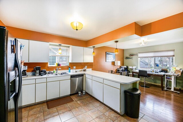 kitchen featuring stainless steel dishwasher, white cabinetry, a peninsula, and plenty of natural light