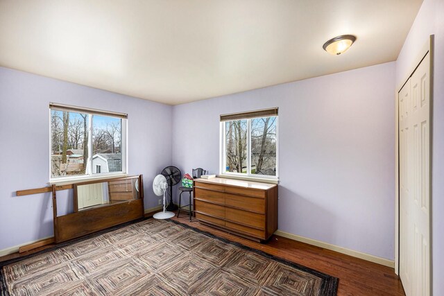 bedroom featuring baseboards, wood finished floors, and multiple windows